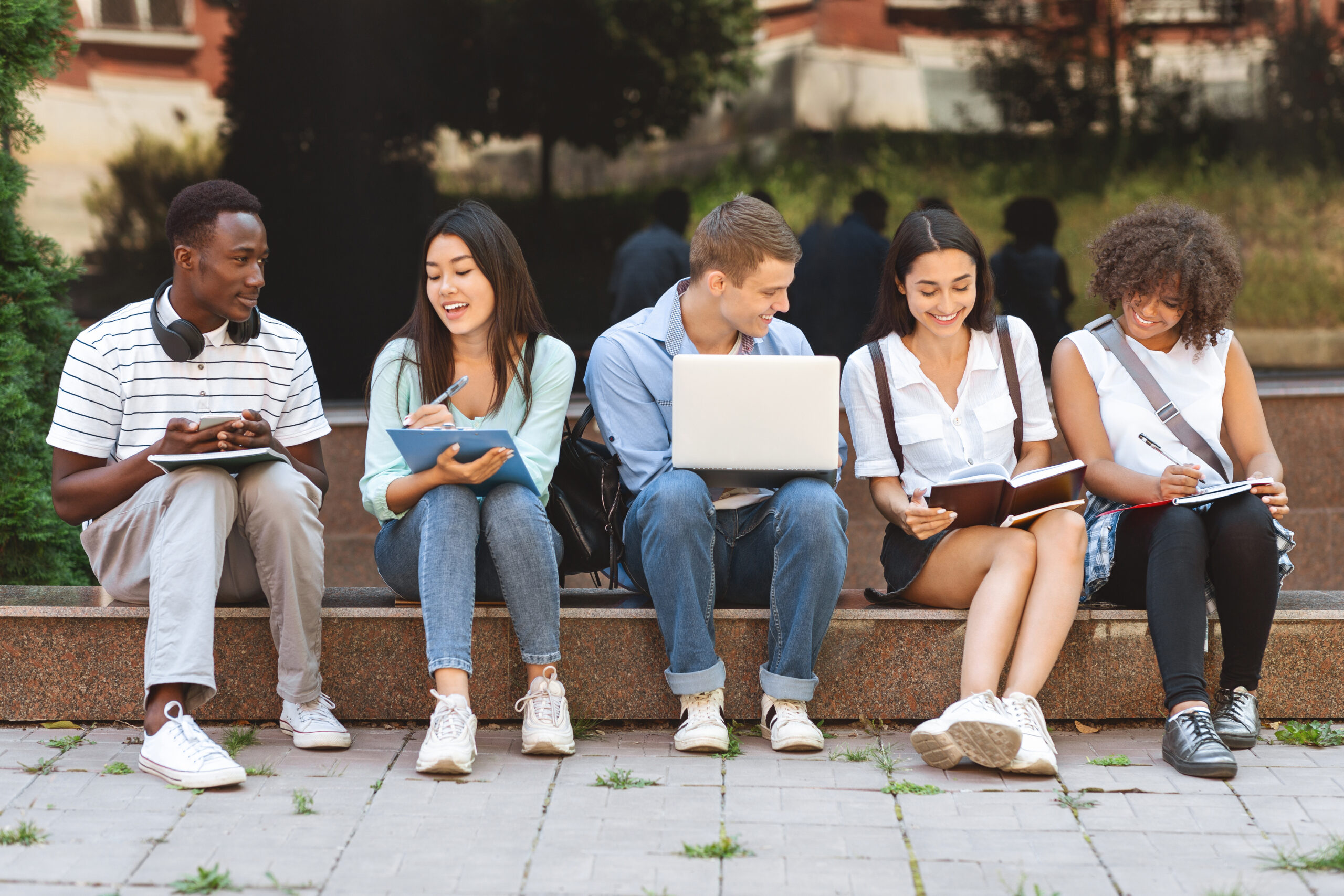 Group of happy teen students studying outdoors